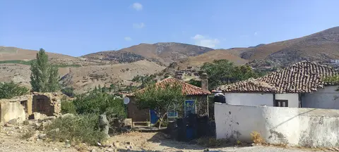 Gökçeada Dereköy'de kiremit çatılı beyaz evler ve arkadaki çıplak tepeler