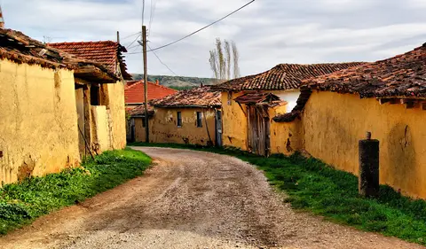 Yenişehir'e bağlı Kavaklı'da toprak yolun iki yanında sarı sıvalı, kiremit çatılı evler