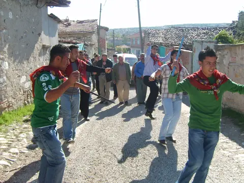 Kula'ya bağlı Körez'de taş evler arasındaki sokakta boyunlarında yemeniyle oynayan düğün alayı