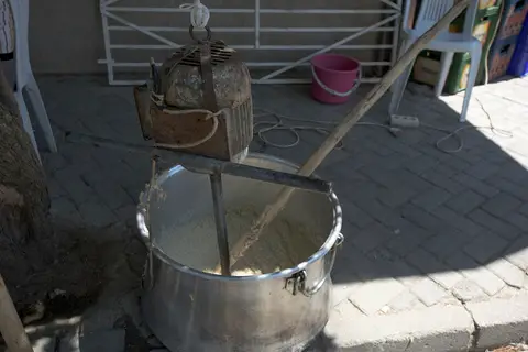 Kaldırımda büyük kazanın içinde uzun tahta tokmakla dövülen keşkek
