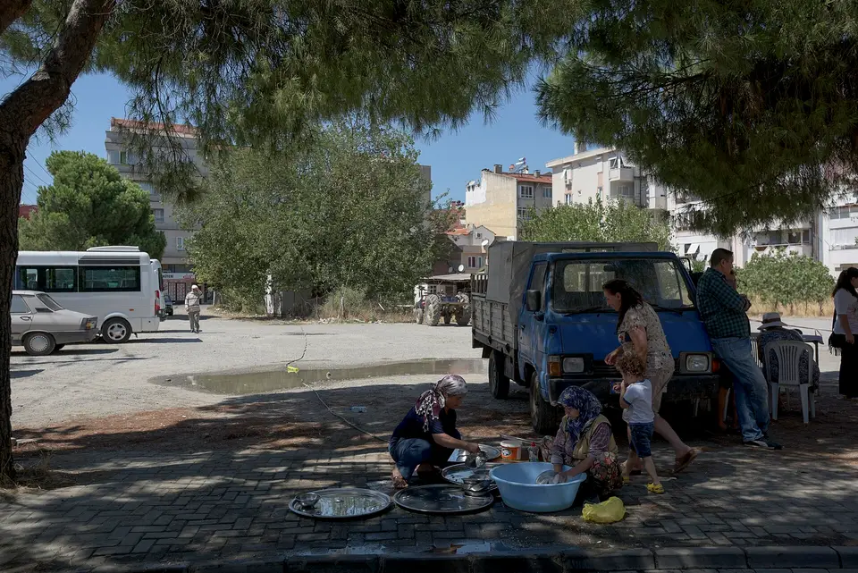 Ağaçlı bir sokakta keşkek kazanlarının başında hazırlık yapan kalabalık