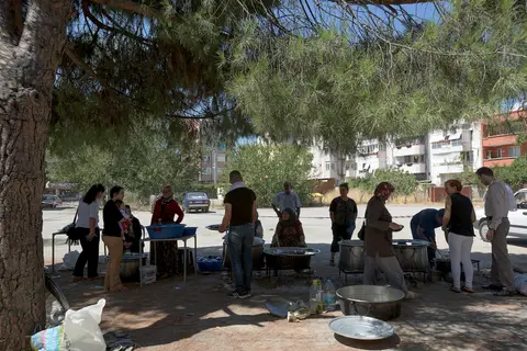 Çam ağaçlarının gölgesinde kazanların başında keşkek hazırlığı yapan kalabalık