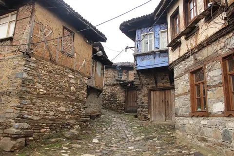 Cumalıkızık'ta taş zeminli dar sokağın iki yanında taş ve ahşaptan çıkmalı köy evleri