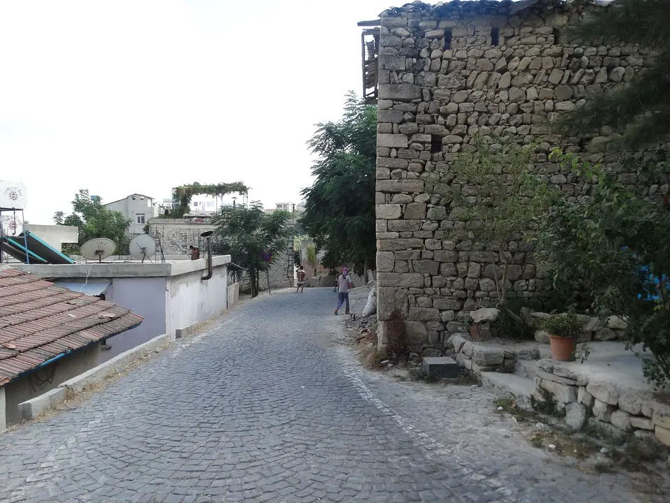 Hıdırbey köyünde taş duvarlı evler arasından geçen parke taşlı sokak