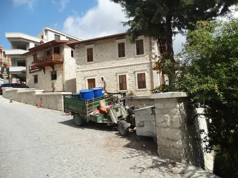 Samandağ'a bağlı Hıdırbey'de taş evlerin önünde park etmiş küçük traktör ve dar sokak