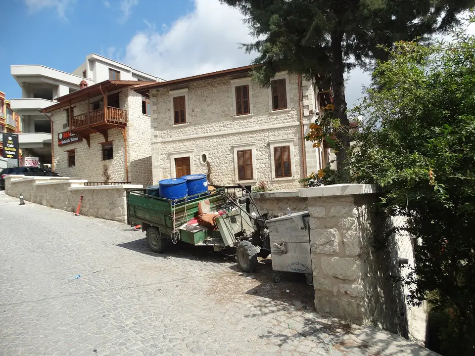 Samandağ'a bağlı Hıdırbey'de taş evlerin önünde park etmiş küçük traktör ve dar sokak