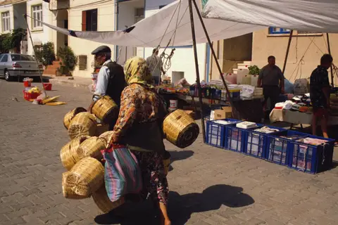 Bozcaada'da pazar yerinde sepetler taşıyan bir satıcı