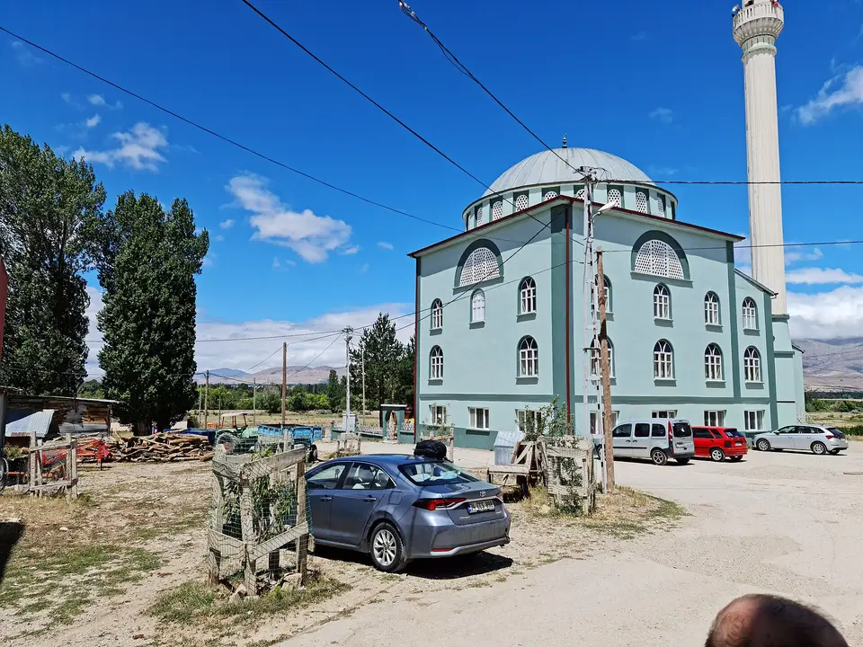 Bayburt'ta Aşağı Dikmetaş köyünde açık yeşil boyalı kubbeli cami ve önündeki toprak meydan