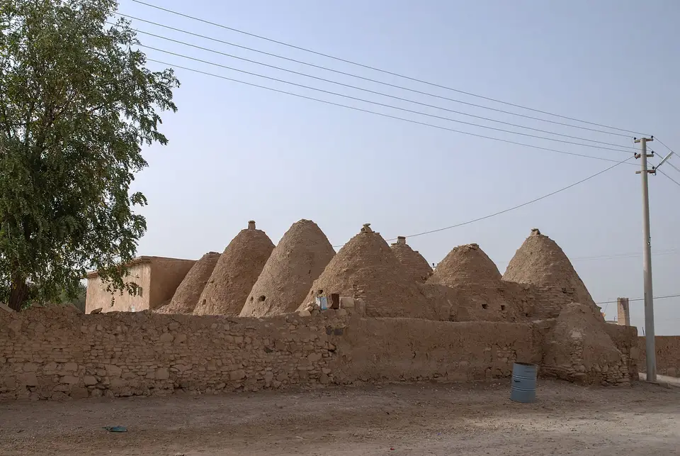 Şanlıurfa Harran'da kerpiç duvarın ardında sıralanan konik kubbeli kümbet evler