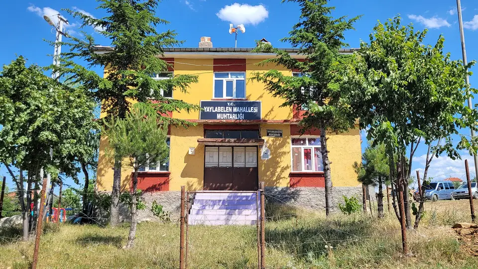 Akşehir'e bağlı Yaylabelen'de ağaçlar arasındaki iki katlı muhtarlık binası