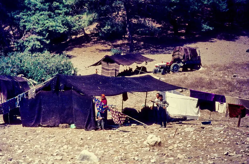 Toroslar'da Akkaya Yaylası'nda ağaçlar altında kurulmuş kara çadırlar ve yanında traktör