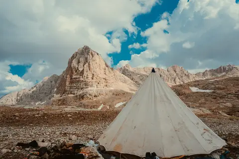 Aladağlar'da sarp kayalık zirvelerin önünde kurulmuş beyaz konik çadır