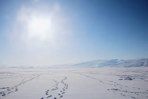 Kar altındaki donmuş Çıldır Gölü yüzeyinde ayak izleri ve uzakta karlı tepeler